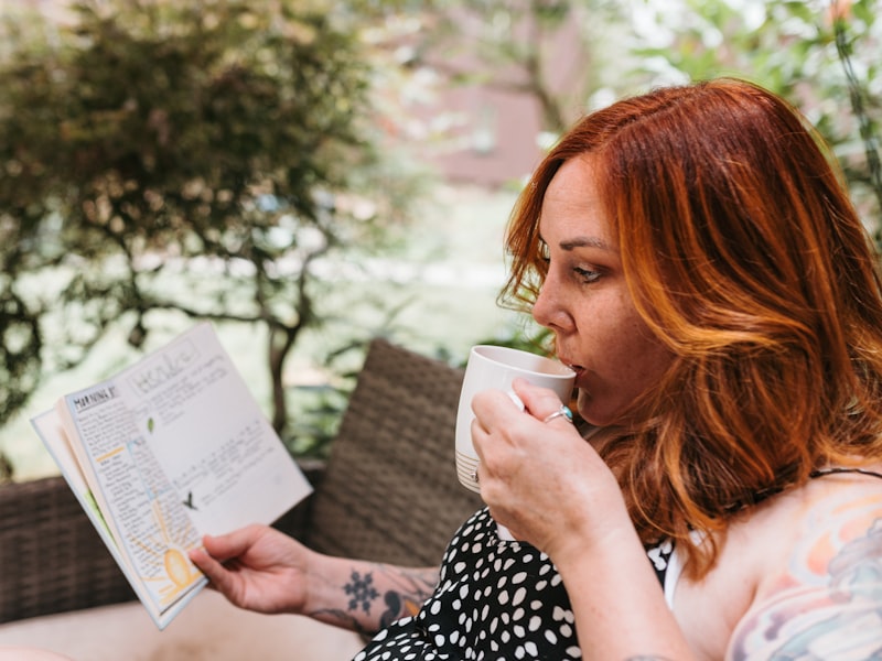 Woman drinking coffee and reading a journal in soft morning light