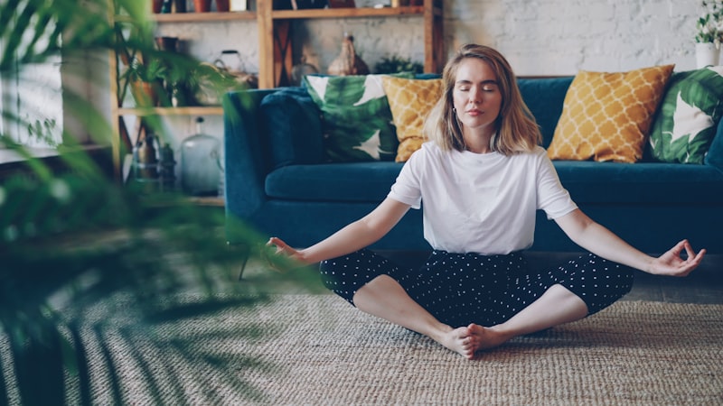 Woman meditating cross-legged on the floor at home